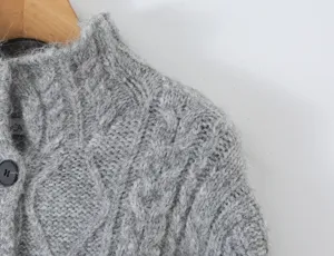 Close-up detail van de grijze kabelbreisel cardigan trui kraag textuur, stijlvolle winterkleding.