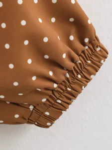 Brown polka dot windbreaker sleeve cuff detail, elastic gathered design, close up view.