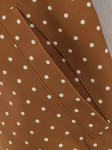 Detail view of brown polka dot trench coat pocket, stylish women outer fabric close up.