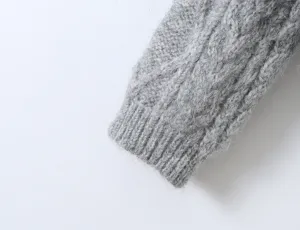 Close-up van de grijze kabelbreisel trui mouw, met zachte textuur en geribbelde manchetten.