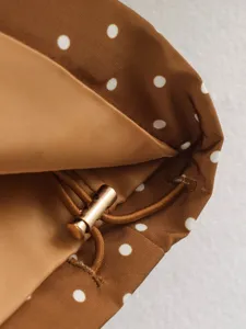 Close-up detail of women's polka dot windbreaker with drawstring and stylish metal buckle.