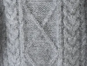 Detailopname van grijze kabelgebreide truistof met zachte woltextuur en een mooi patroon.