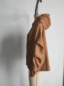 Brown polka dot hooded windbreaker jacket detail view showing side profile on mannequin.
