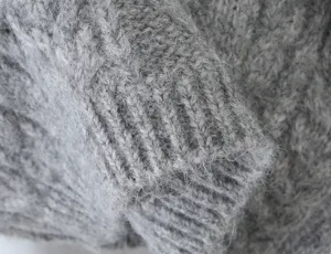 Grijs pluizig cardigan trui mouw manchet close up textuur detail zachte wol stof materiaal
