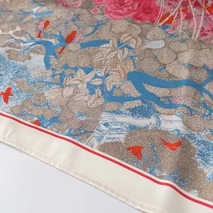 Close-up detail of luxury floral and bird printed silk scarf with elegant rolled hem design.