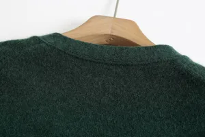 Green V-neck knit cardigan detail close-up showing soft textured fabric and collar craftsmanship.