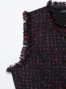 Dettaglio gilet smanicato in tweed da donna con fili metallici rossi e bordi sfrangiati.