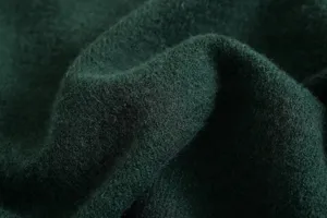 Detailed close-up of dark green knitted cardigan fabric, soft wool texture and cozy look.