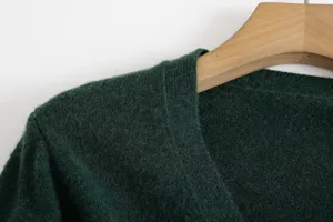 Close-up detail of dark green knit V-neck cardigan shoulder texture and soft fabric.