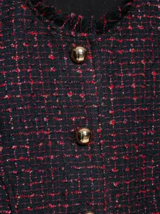 Primo piano di gilet in tweed da donna con fili metallici e bottoni dorati, texture dettagliata.