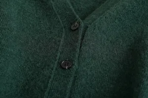 Dark green knitted cardigan detail showing V-neck placket and black buttons closeup.