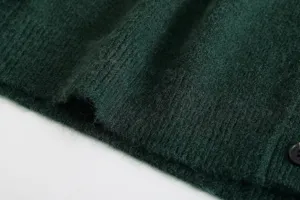 Dark green knitted cardigan fabric detail shot, cozy fuzzy texture with ribbed hem and button.