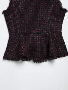 Vista dettagliata del top smanicato in tweed nero e rosso con eleganti finiture frangiate.