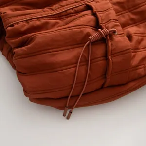 Detail shot of women's quilted puffer coat drawstring and horizontal stitching texture.