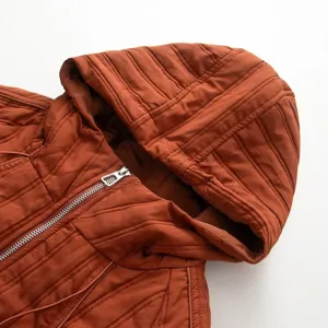 Close-up detail of the stylish hooded quilted cotton coat, featuring zipper and collar.