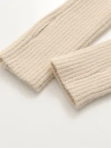 Gros plan sur les poignets en tricot côtelé beige, texture douce et finition soignée.