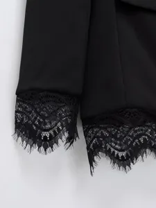 Detailopname van een elegante zwarte blazer met delicate kanten manchetten en zoom.