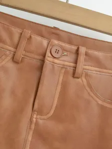 Brown PU leather skirt detail view, featuring classic button, waist loops, and fine stitching.