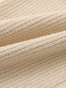 Gros plan sur la texture du tissu tricoté côtelé doux en beige, montrant une matière duveteuse.