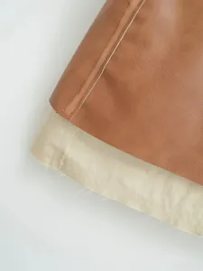 Close-up detail of stylish PU leather color-block skirt, textured fabric with contrast stitching.