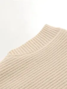 Gros plan du col roulé en tricot côtelé beige, texture douce, détail automnal.