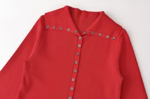 Detalle del cárdigan rojo de punto que muestra los botones y el diseño único del cuello.