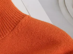 Orangener Rippstrick Pullover Kragen Detail, weiche gemütliche Stofftextur Nahaufnahme für Damen.