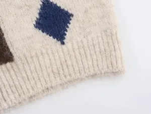 Primer plano del detalle del chaleco de punto con patrón de rombos y dobladillo acanalado.