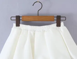 White bubble mini skirt detail showing elastic waist and soft fabric on a wooden hanger.