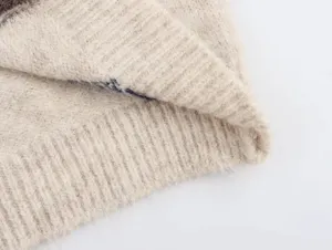 Primer plano detallado de tejido de chaleco de punto beige suave, textura esponjosa y ribetes.