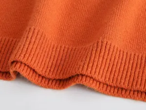 Detaillierter Blick auf den orangen Strickpullover mit weicher Textur und Rippsaum.