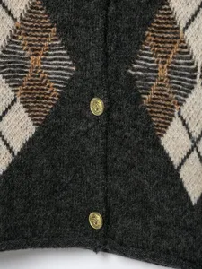 Gros plan détaillé du cardigan en tricot argyle élégant avec des boutons en métal doré.