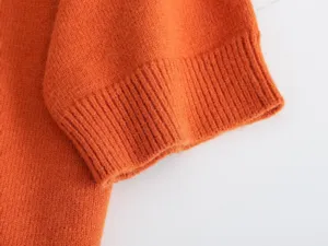 Nahaufnahme des orangefarbenen Strickpullover-Bündchens mit feiner Rippenstrick-Struktur.