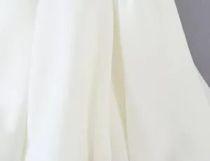 White pleated fabric texture detail shot, elegant clothing material close-up view.