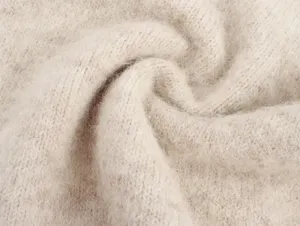 Primer plano de la textura suave y esponjosa del tejido de punto beige, material acogedor.