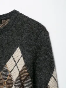 Gros plan détaillé du pull en tricot gris foncé avec un motif losanges classique et texture.