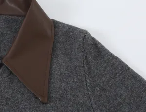Close-up view of a chic grey knit cardigan featuring a contrast brown leather lapel detail.