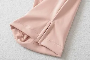 Detailopname van roze stretch yogabroek met stijlvolle split bij de boord en zachte stof.