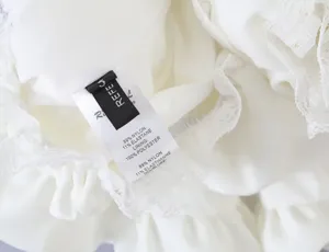 Detail view of white lace flare skirt fabric and brand care label showing material composition.