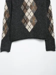 Gros plan détaillé du pull en tricot gris foncé avec motif losange argyle sur les manches.
