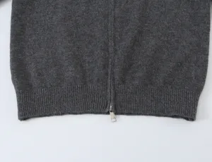 Close-up detail of dark gray knit cardigan hem and metal zipper, fine ribbed texture view.
