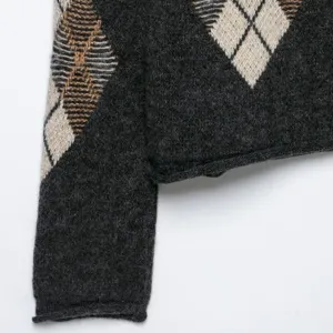 Cardigan en tricot gris foncé à motif argyle, vue détaillée de la manche et de l'ourlet.