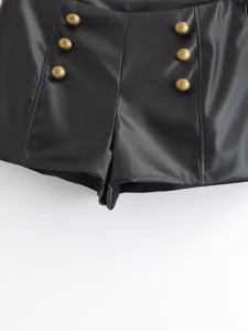 Close up detail of womens black faux leather high waist shorts featuring stylish antique metal buttons.