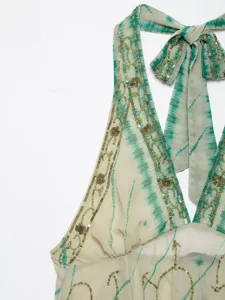 Close-up view of a green tie-dye halter neck top featuring exquisite sequin embroidery and straps.