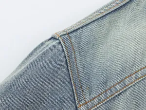 Detailopname van de schoudernaad van een blauw gewassen denim jas, sterke stiksels.