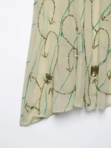 Close-up detail of women's halter top featuring delicate sequin embroidery and tie-dye lines.
