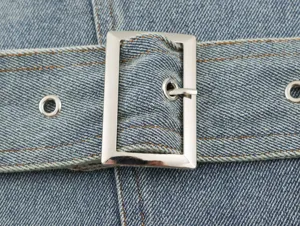 Close-up detail van een dames denim jasje riem gesp met metalen gesp en stiksels.