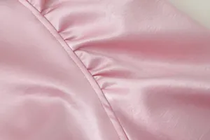 Rosa Satinstoff Kleidungsstück Detail, elegante geraffte Textur und saubere Nähte.