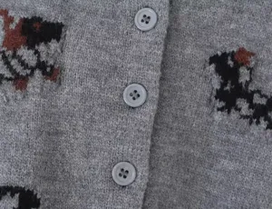 Grey knit cardigan detail showcasing fine texture, contrast dog jacquard, and front buttons.
