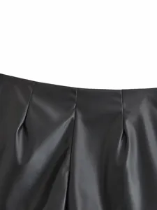 Close-up detail of black faux leather shorts waist with pleats, stylish fashion apparel part.